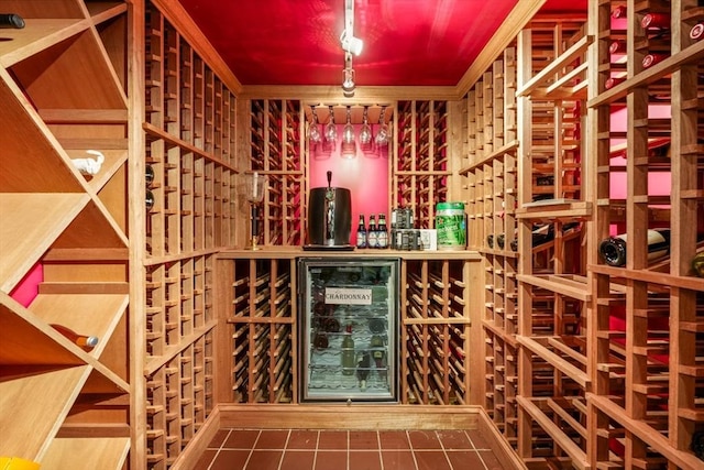 wine area with tile patterned floors, wine cooler, and ornamental molding