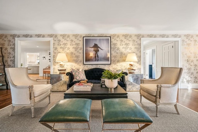 living room with wallpapered walls, crown molding, wood finished floors, and baseboards