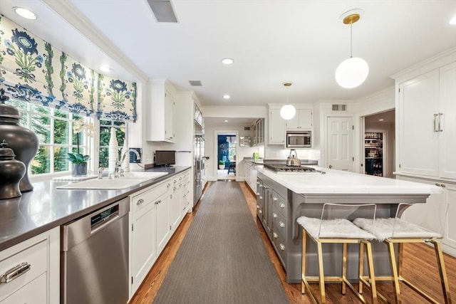 kitchen featuring a sink, appliances with stainless steel finishes, white cabinets, and a center island