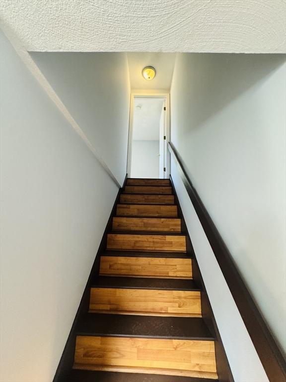 stairway featuring a textured ceiling