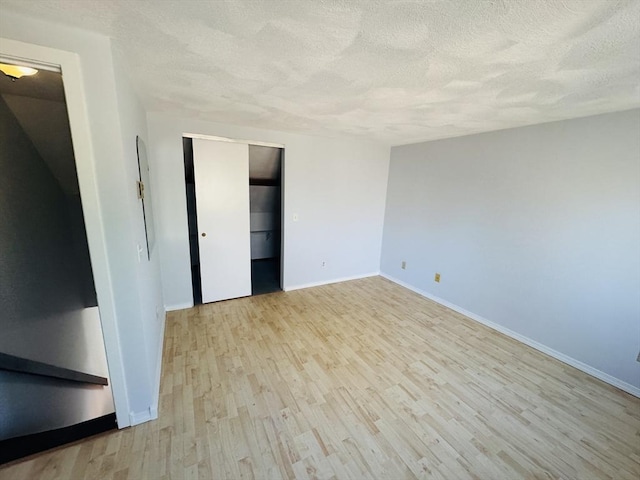 interior space featuring a closet, baseboards, a textured ceiling, and wood finished floors