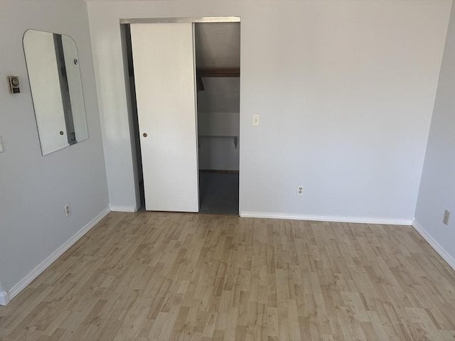 unfurnished bedroom featuring electric panel, wood finished floors, a closet, and baseboards