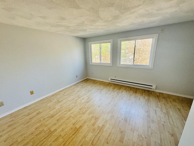 unfurnished room featuring a baseboard heating unit, baseboards, a textured ceiling, and wood finished floors