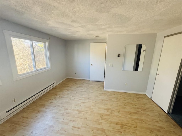 unfurnished room with light wood finished floors, baseboard heating, a textured ceiling, and baseboards