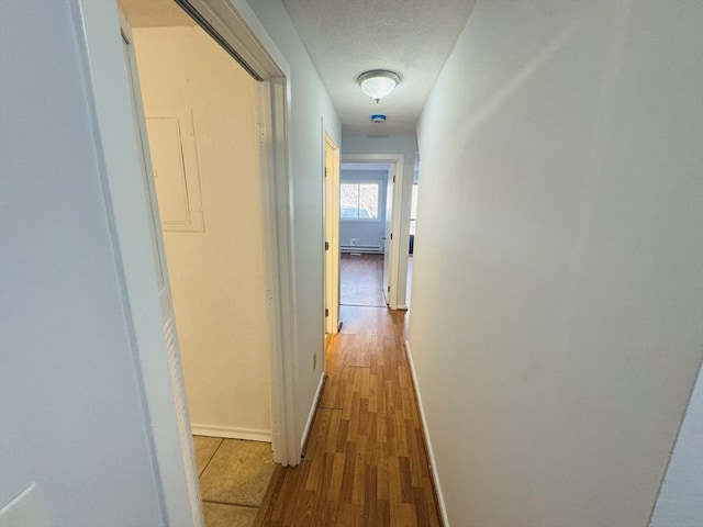 hallway featuring baseboards, a textured ceiling, and wood finished floors