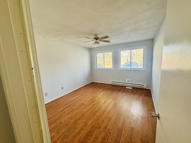 unfurnished room featuring a baseboard heating unit, baseboards, ceiling fan, wood finished floors, and a textured ceiling