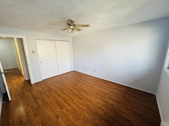 unfurnished bedroom featuring wood finished floors, baseboards, ceiling fan, a closet, and a textured ceiling