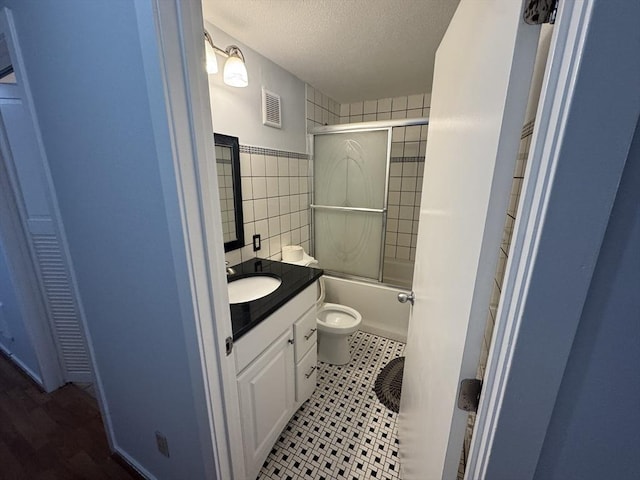 full bath featuring visible vents, toilet, a textured ceiling, tile walls, and vanity