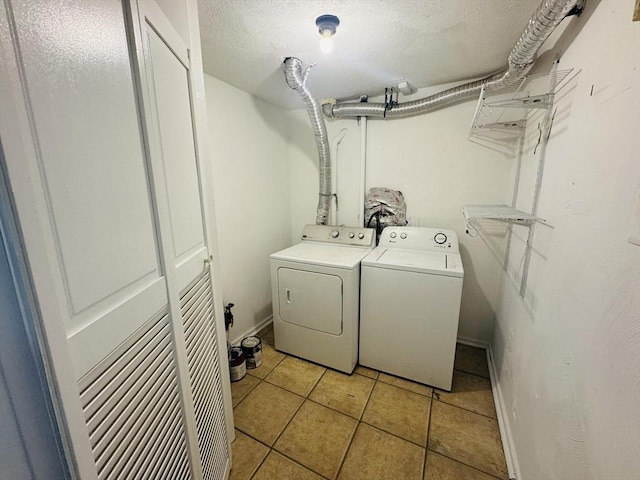 washroom with baseboards, laundry area, light tile patterned flooring, a textured ceiling, and separate washer and dryer