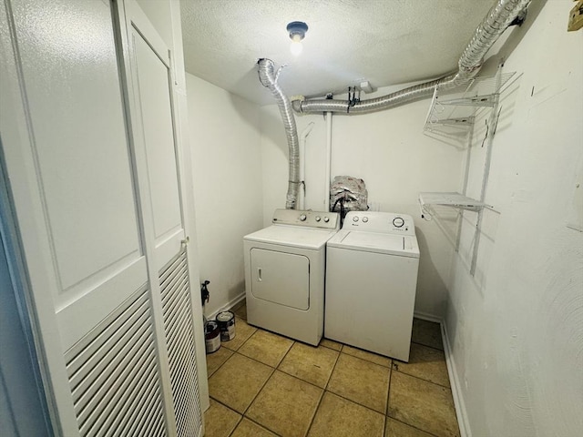 clothes washing area featuring washer and clothes dryer, a textured ceiling, light tile patterned floors, baseboards, and laundry area