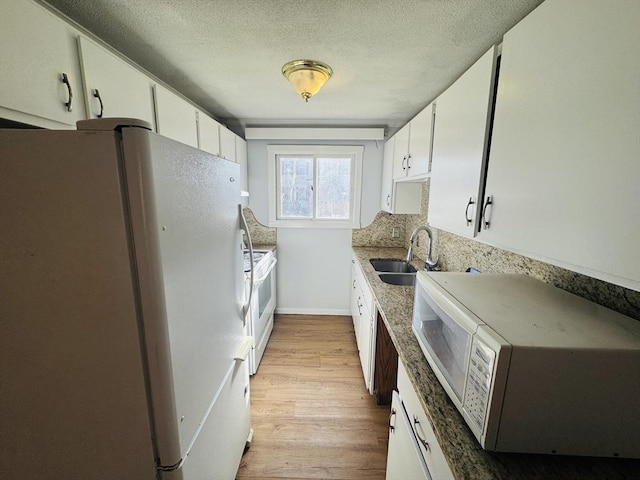 kitchen featuring white cabinetry, white appliances, light wood finished floors, and a sink