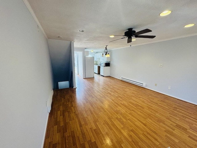 unfurnished living room with crown molding, light wood-style floors, baseboard heating, and a textured ceiling