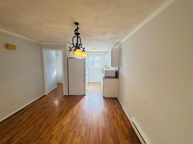 unfurnished dining area featuring a chandelier, ornamental molding, baseboards, and wood finished floors