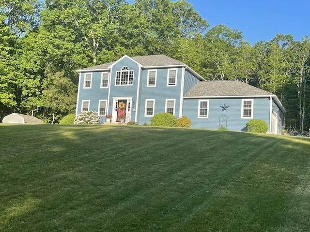 colonial house with a front lawn and roof with shingles