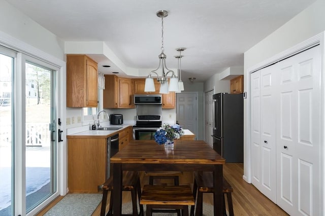 kitchen featuring stainless steel appliances, light countertops, an inviting chandelier, a sink, and wood finished floors