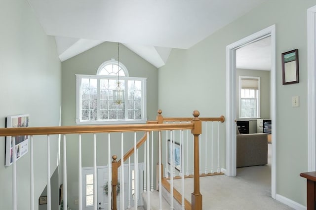 hall featuring carpet floors, vaulted ceiling, plenty of natural light, and an upstairs landing