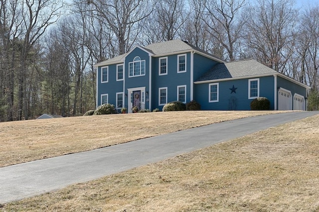 colonial house with a garage, a front lawn, and aphalt driveway