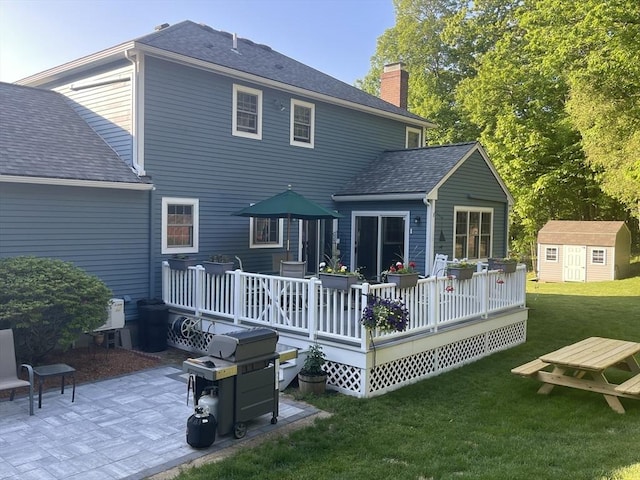 back of property featuring a yard, a chimney, a patio area, a shed, and an outdoor structure