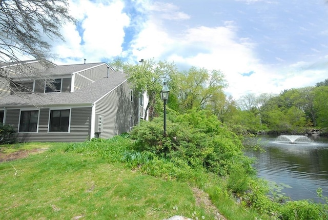 view of side of property with a water view and roof with shingles