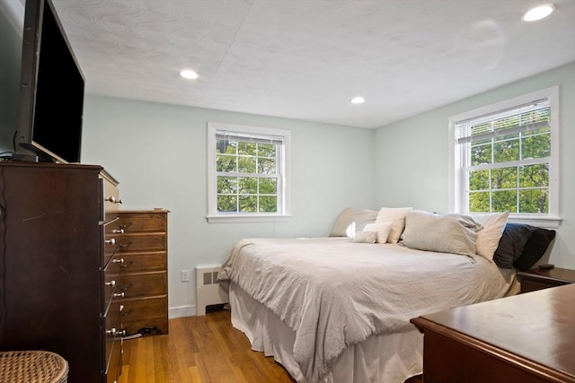bedroom with wood finished floors, recessed lighting, and baseboards