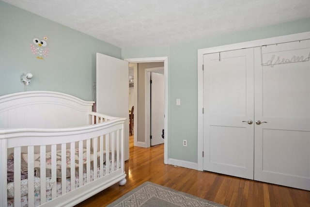 bedroom with a closet, wood finished floors, and baseboards