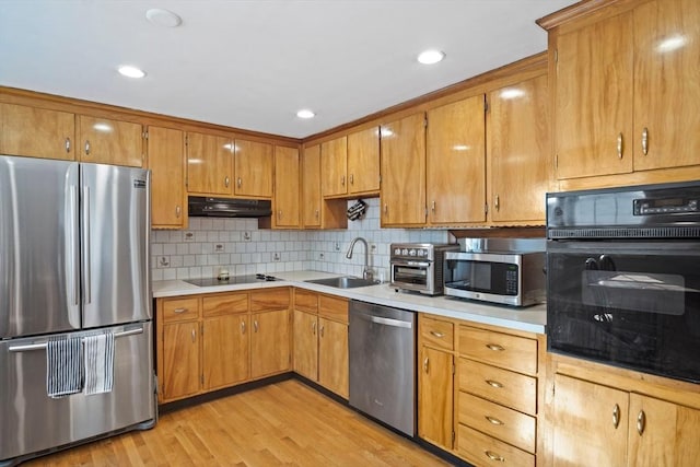 kitchen featuring black appliances, a sink, under cabinet range hood, light countertops, and recessed lighting
