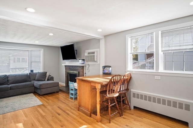 bar with radiator, light wood-type flooring, a brick fireplace, an AC wall unit, and recessed lighting
