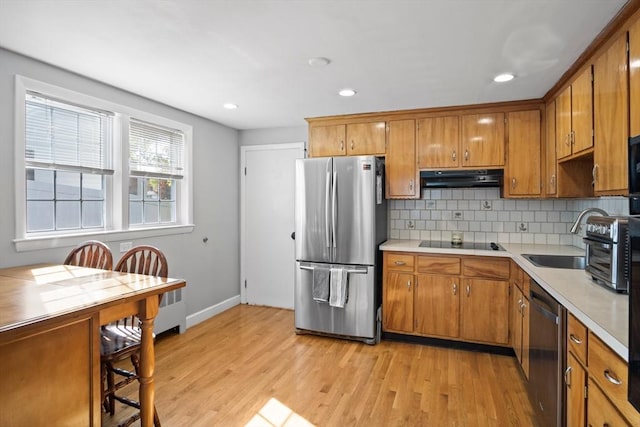 kitchen featuring stainless steel appliances, under cabinet range hood, brown cabinets, light countertops, and recessed lighting