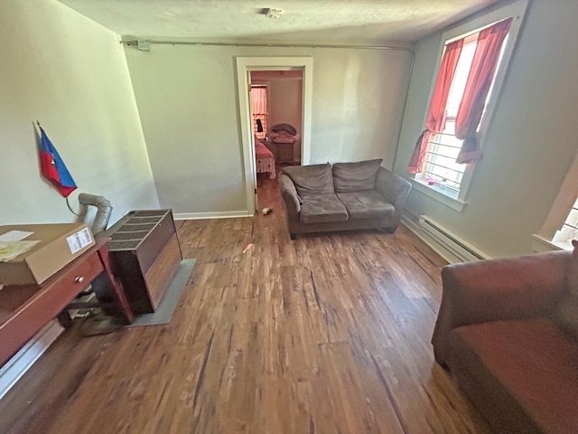 living area with dark wood-type flooring, a textured ceiling, and a baseboard heating unit