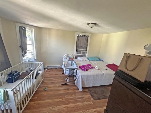 bedroom with dark hardwood / wood-style flooring and a baseboard heating unit