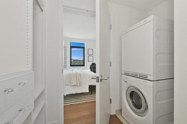 laundry room featuring laundry area, dark wood finished floors, and stacked washer and clothes dryer