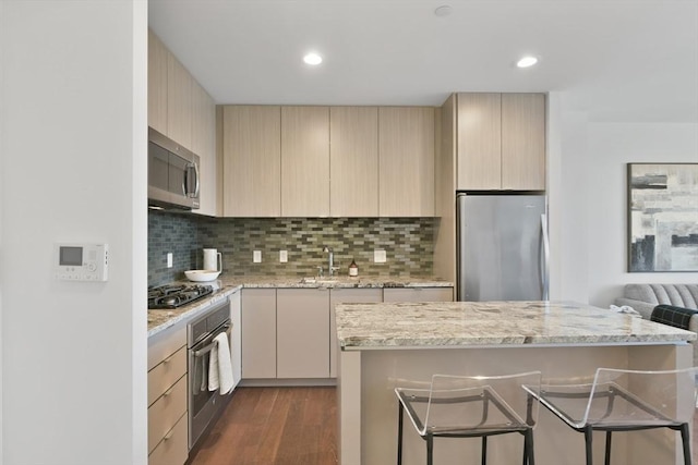 kitchen featuring dark wood finished floors, tasteful backsplash, appliances with stainless steel finishes, light brown cabinets, and modern cabinets