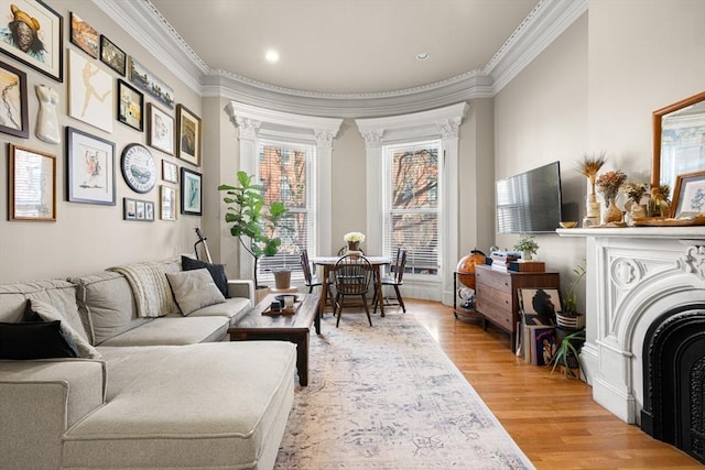 living room with a fireplace, crown molding, decorative columns, recessed lighting, and light wood-style flooring