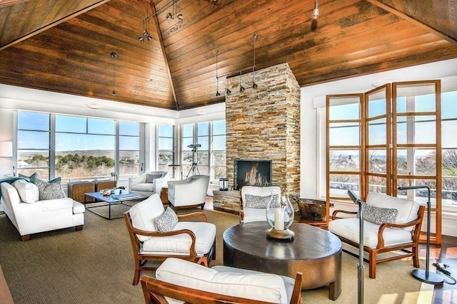 carpeted living room with a stone fireplace, wood ceiling, high vaulted ceiling, and a wealth of natural light