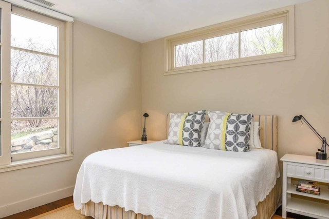 bedroom with hardwood / wood-style flooring and multiple windows