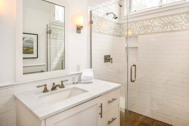 bathroom with tile walls, a shower with door, and vanity