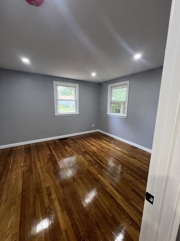 spare room featuring dark hardwood / wood-style flooring and a healthy amount of sunlight