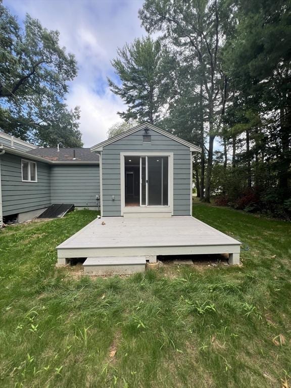 back of property featuring a deck and a lawn