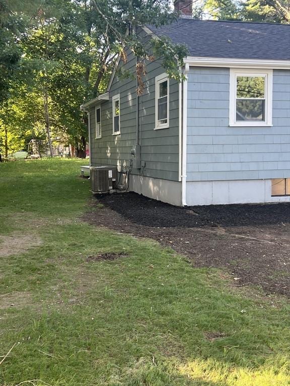 view of side of property with central AC and a lawn