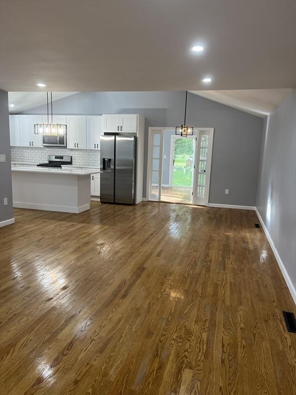 unfurnished living room featuring lofted ceiling and dark hardwood / wood-style floors