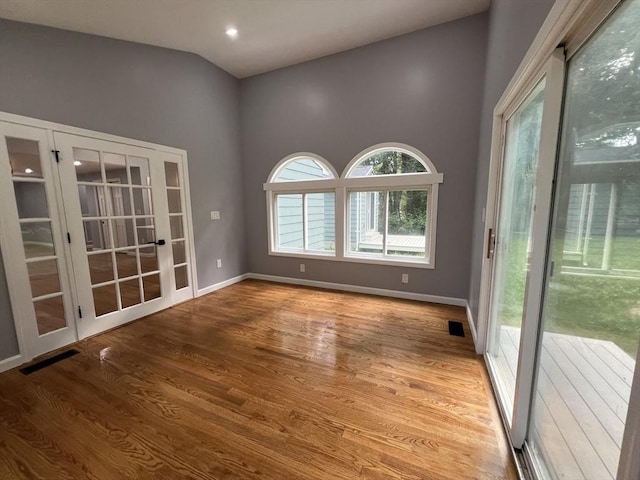 spare room featuring lofted ceiling, french doors, and light wood-type flooring