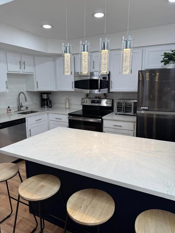 159 Tall Oaks Dr Unit H, Weymouth, MA 02190 - kitchen featuring appliances with stainless steel finishes, a sink, a kitchen bar, backsplash, and white cabinets