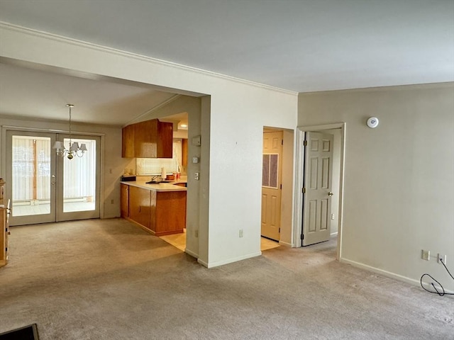 unfurnished living room with light carpet, a chandelier, and crown molding