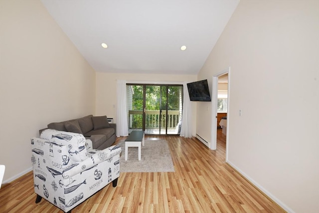 living room featuring vaulted ceiling, baseboard heating, and light wood-type flooring