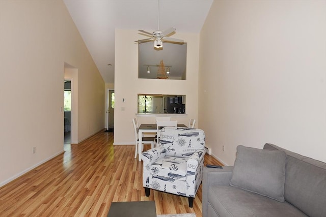 living room with ceiling fan, high vaulted ceiling, and light hardwood / wood-style flooring