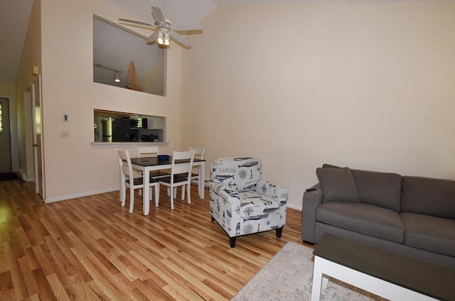 living room featuring high vaulted ceiling, ceiling fan, and light wood-type flooring