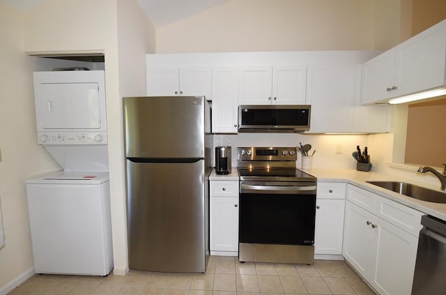 kitchen featuring stainless steel appliances, stacked washing maching and dryer, sink, and white cabinets