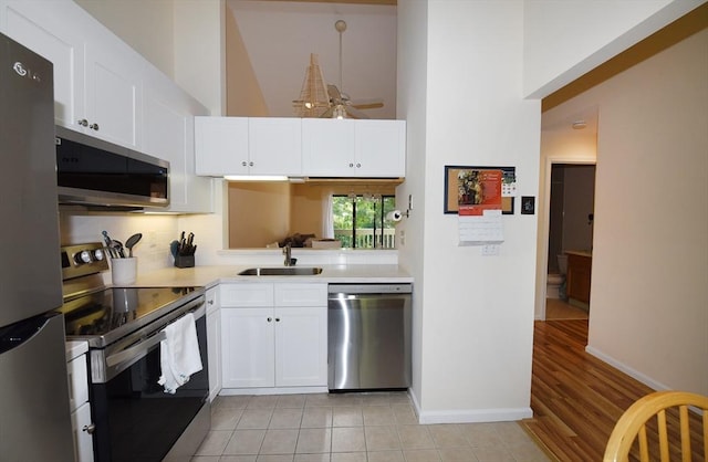 kitchen with sink, a high ceiling, white cabinets, and appliances with stainless steel finishes