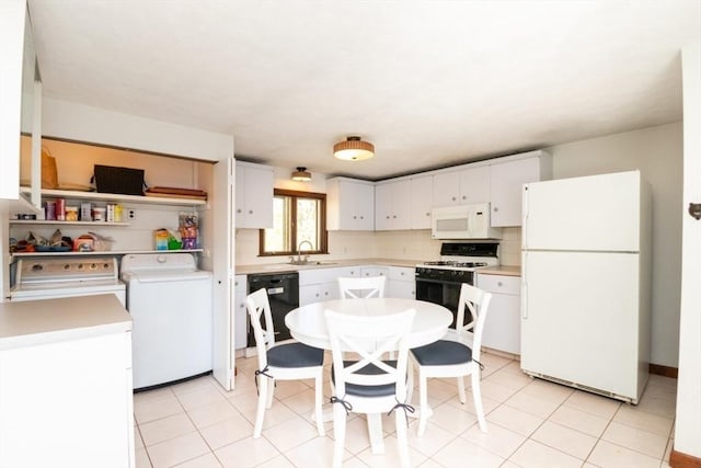 kitchen with a sink, light countertops, white appliances, white cabinetry, and washer and dryer