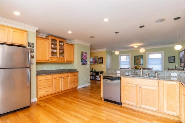 kitchen featuring light brown cabinetry, glass insert cabinets, ornamental molding, stainless steel appliances, and light wood-style flooring